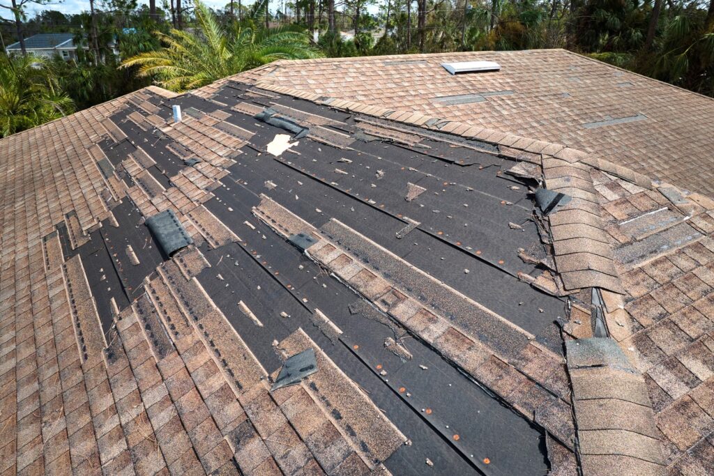 Residential roof with missing shingles caused by strong winds.