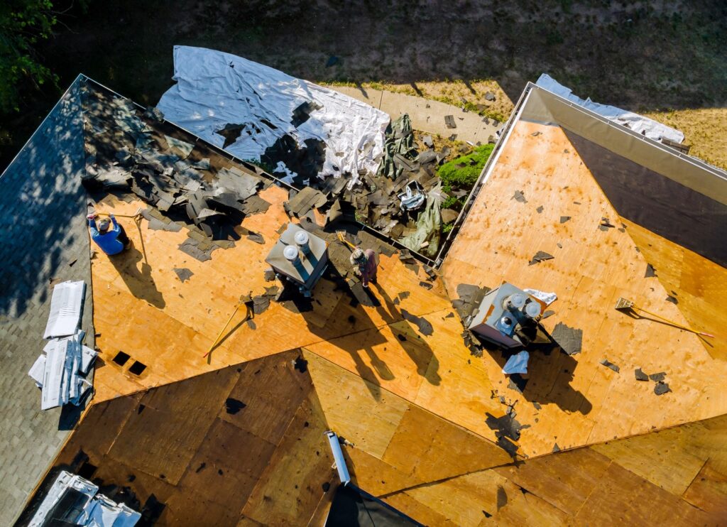 Roofer inspecting storm-damaged roof during emergency repair.